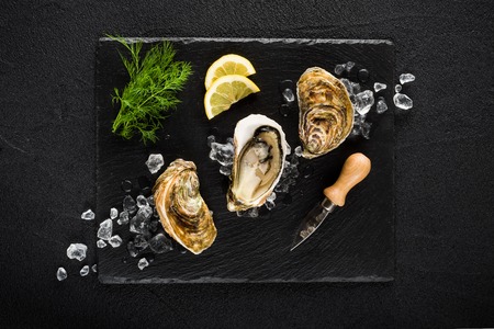 Fresh oysters on a black stone plate top viewの写真素材