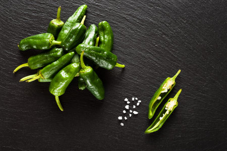 Raw pimientos de padron on black background top view