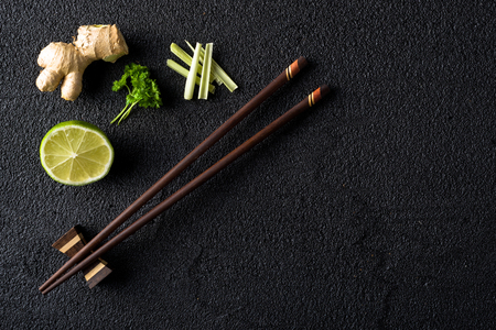 Chopsticks and food ingredients on black stone table top viewの写真素材