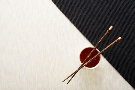 Chopsticks and bowl with sauce on table mat top viewの写真素材