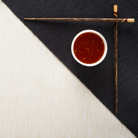 Chopsticks and bowl with sauce on table mat top viewの写真素材
