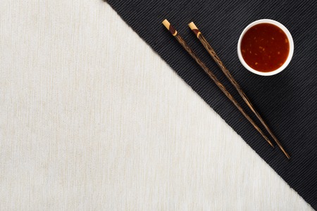 Chopsticks and bowl with sauce on table mat top viewの写真素材