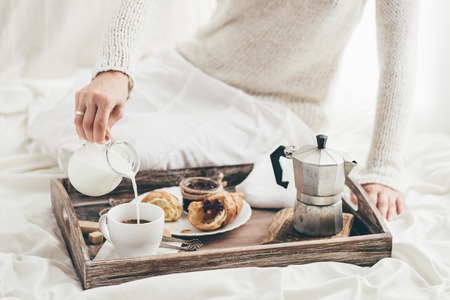 Woman having breakfast in bed. Window lightの写真素材