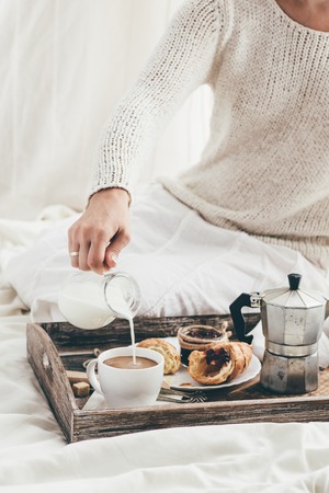 Woman having breakfast in bed. Window lightの写真素材