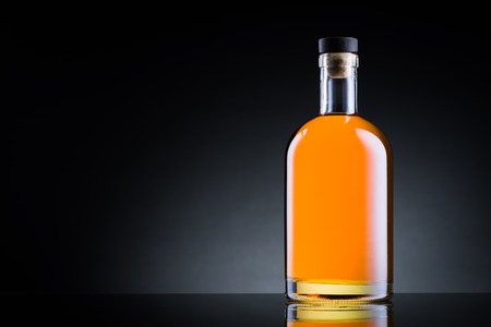 Whiskey bottle on black glass surfaceの写真素材