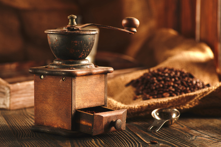 Coffee grinder and bag of roasted coffee on wooden table.の写真素材