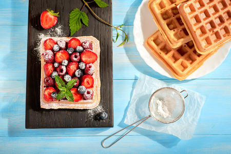 Waffles with strawberry and berry fruit on blue table top viewの写真素材