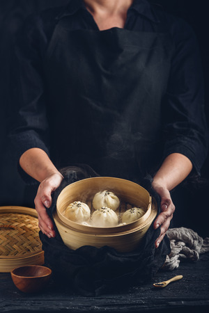 Woman presenting dim sum dumplings in steamerの写真素材