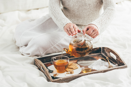 Woman and warming tea in bed. Window lightの写真素材