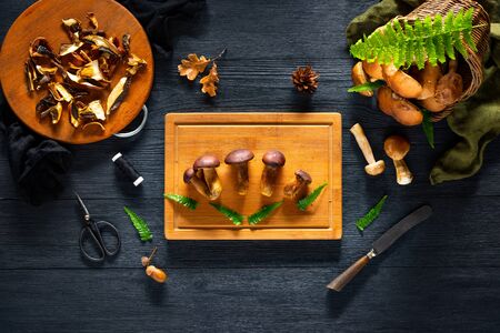 Forest mushroom on the cutting board on a black table.の写真素材
