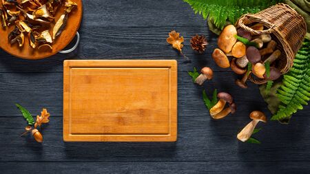 Forest mushroom and cutting board on black table. Copy spaceの写真素材