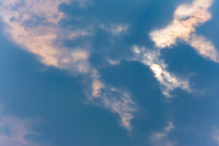 Close-up photo of Blue cloudy sky in the mid-day, with sun covered by the cloud peekingの写真素材