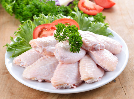 Raw chicken wings with vegetables on wooden boardの写真素材