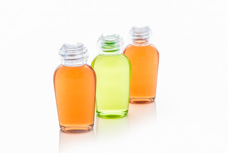 Orange and green bottles of shampoo, gel, soap on a white background with reflectionの写真素材