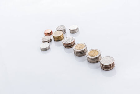 Arrow made out of thai coins isolated on a white background pointing upの写真素材