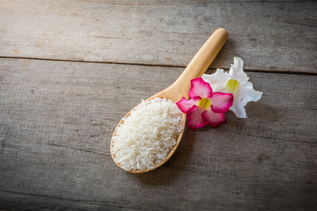 Rice on Wooden Spoons on wooden background and pink , white flower, still lifeの写真素材