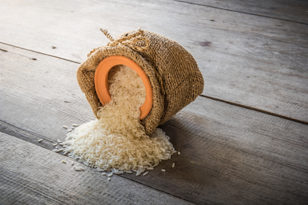rice and clay pot in sack bag on wooden backgroundの写真素材