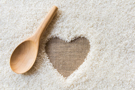 wooden Spoon on rice background Space in the middle of a heart. sackcloth is backgroundの写真素材