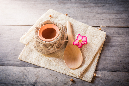 clay pot in sack bag and wooden spoon on wooden backgroundの写真素材