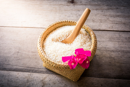 Wooden Spoons and basket of jasmine rice on wooden backgroundの写真素材