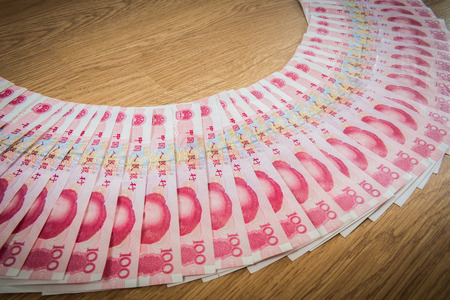 closeup 100 Yuan, Chinese money arranged in a circle on wooden backgroundの写真素材