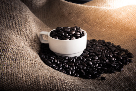 Cup full of coffee beans on the cloth sack. retro colorsの写真素材