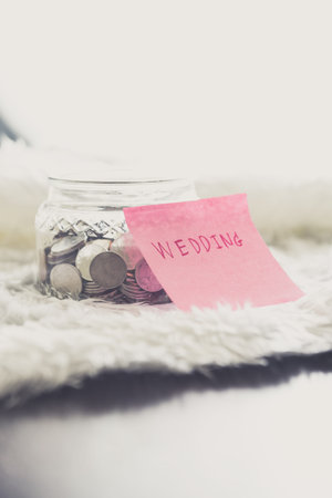 many coins in a money jar with wedding label on jar. wedding concept. saving conceptの写真素材