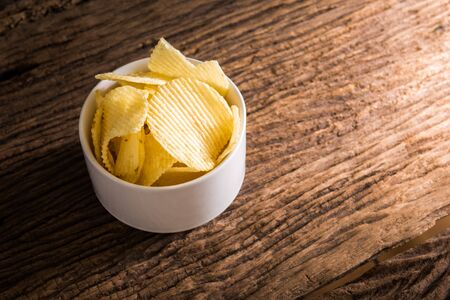 Crispy potato chips on wooden table backgroundの写真素材