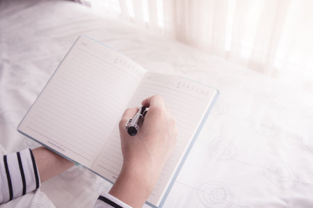 Close-up of female hands holding  pen and opened diary book. retro style photoの写真素材