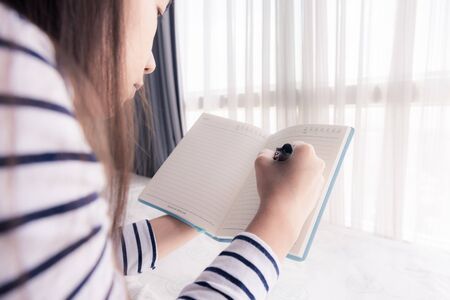 Close-up of female hands holding  pen and opened diary book. retro style photoの写真素材