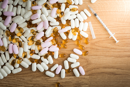 Syringe and pills on wooden backgroundの写真素材