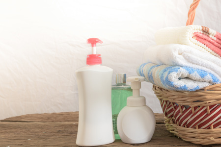Shower gel with Skin cream and bath towels in basket on wooden tableの写真素材