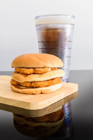 chicken hamburger and glass of cola, wooden cutting board with reflectionsの写真素材