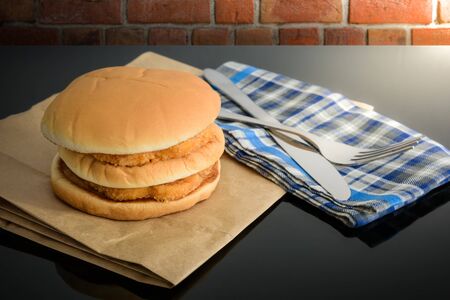 chicken hamburger on brown paper with knife and fork on top table, reflectionsの写真素材