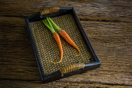 fresh carrots bunch with green leaves in wooden basket on wooden background Vegetable Foodの写真素材