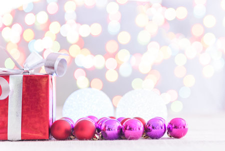 Decorative red gift box with a large silver bow and background bokeh of twinkling party lightsの写真素材