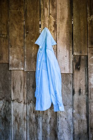 jeans shirt of women hanging on wooden wall backgroundの写真素材