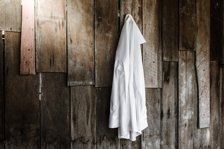 white shirt of women hanging on wooden wall backgroundの写真素材