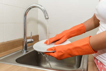 Close up hands of woman washing dishes in kitchenの写真素材