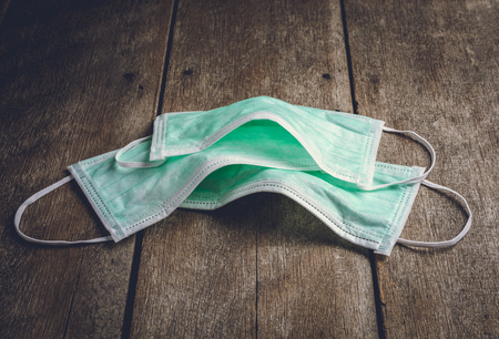 green protective mask on wooden background, medical conceptの写真素材