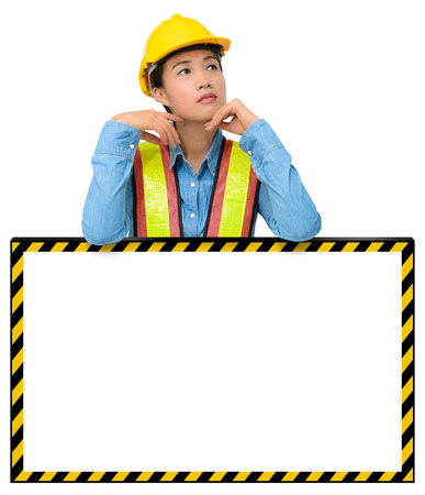 female worker with Protection Equipment, posing behind big white banner, scratching head, looking up and thinking and copy space, isolated on white background with clipping pathの写真素材