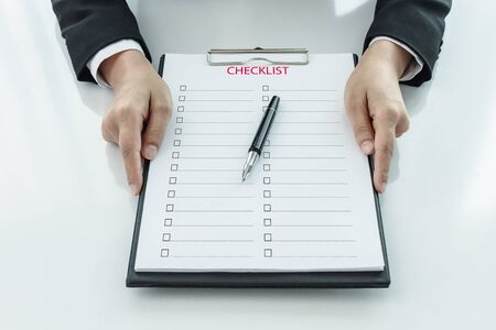 Midsection of businesswoman holding clipboard with checklist againstの写真素材