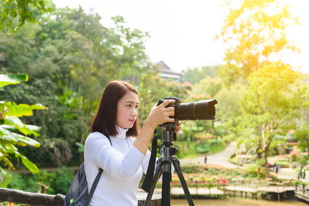 Female photographer with Tripod taking pictures of flowers in flowers gardenの写真素材