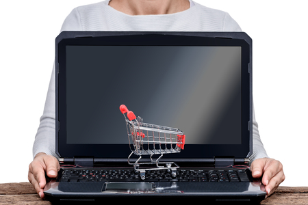 female hand holding Laptop with small shopping cart  isolated in white background with clipping path. online shopping conceptsの写真素材