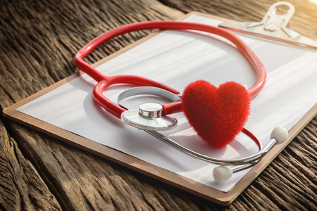 doctor workplace with stethoscope, clipboard and heart at wooden desk, health background concepts.の写真素材