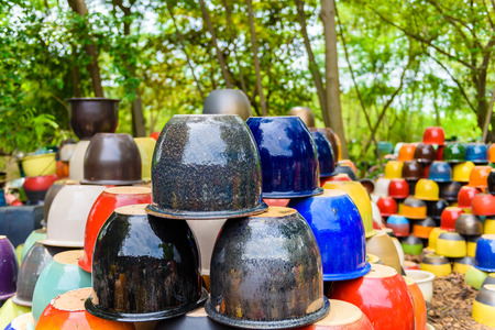 Many different bright multicolored ceramic bowls and cups handcrafted. Placement for gardening and walkways arrangementの写真素材