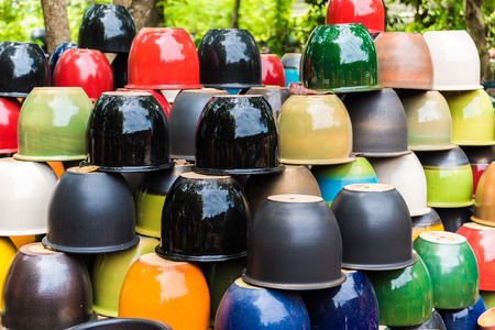 Many different bright multicolored ceramic bowls and cups handcrafted. Placement for gardening and walkways arrangementの写真素材