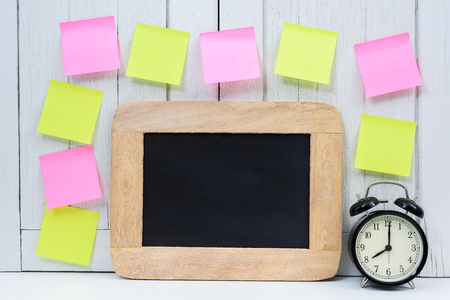 blank space Chalkboard, Alarm clock and blank sticky note, post note  on Office desk white wooden vintage background. dead line, remind or Appointment conceptsの写真素材