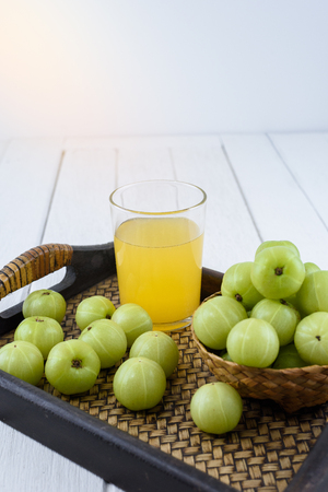 Indian gooseberry in Wooden Tray and juice on white wooden tableの写真素材