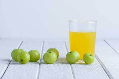 Indian gooseberry and juice on white wooden tableの写真素材